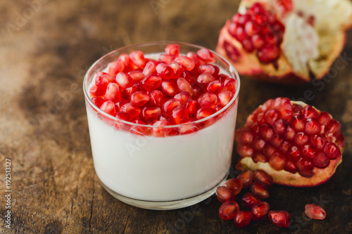 homemade yogurt with pomegranate seeds in jars on an old wooden table