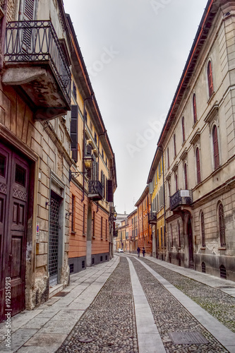 An almost empty street in Cremona in Italy with houses and buildings.