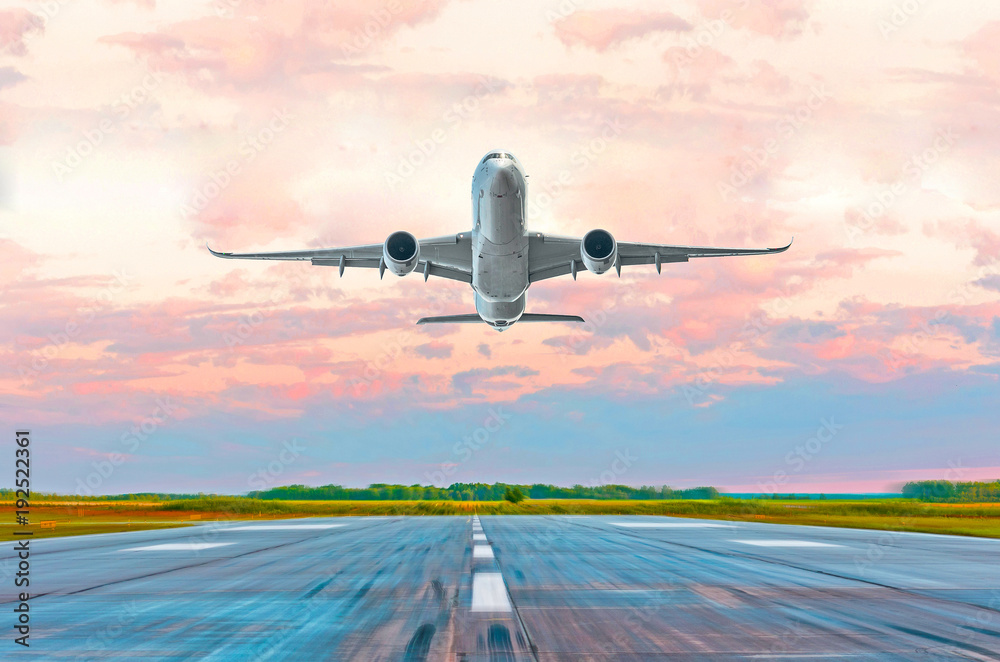 Fototapeta premium Passenger airplane landing at sunset on a runway.