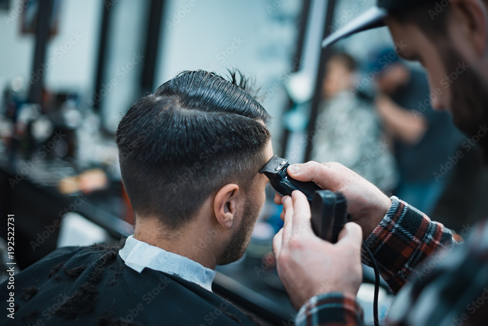 Men's haircut in barbershop. Barber shears clippers. Soft focus.