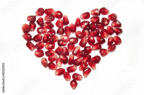 Bright red heart shape from pomegranate seeds isolated on white background, raw juicy fruit