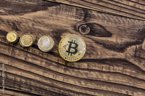  golden bitcoins lie in a pile on wooden table with usual coins