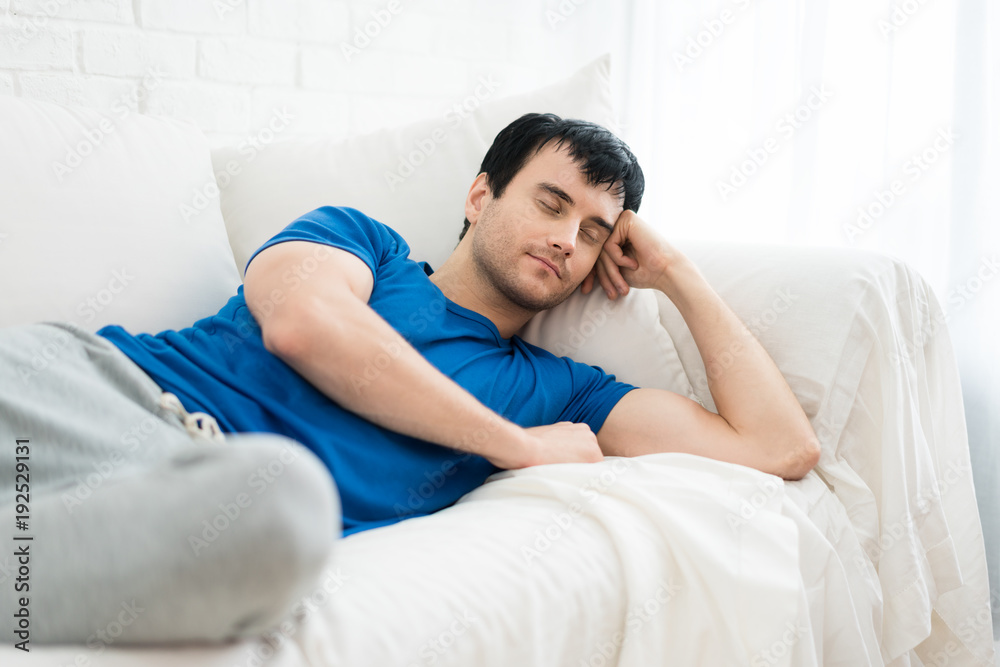 Time to relax. Handsome young man sleeping on the white sofa at home.. Time to relax. Handsome young man sleeping on the white sofa at home..