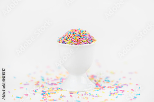 Colorful Pastel Sprinkles in a cup on white backdrop with copy space