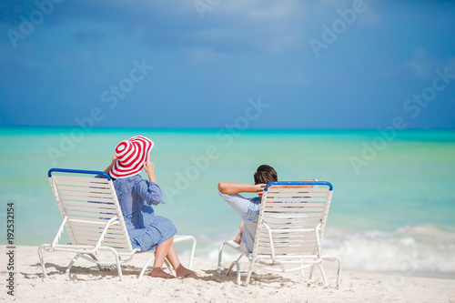 Happy family relaxing on a tropical beach on the beach chairs