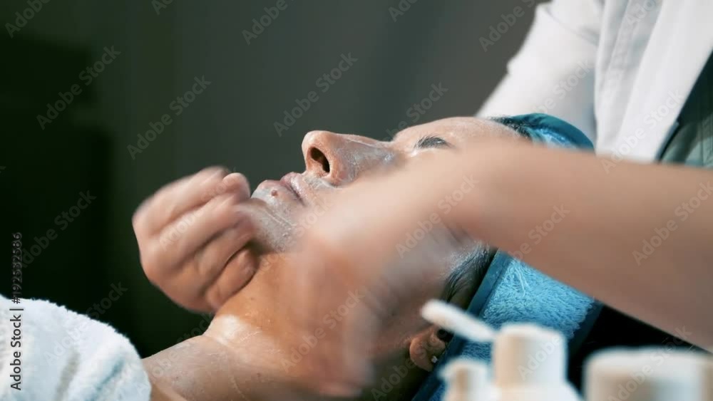 Cosmetologist applying Gold facial mask to the face, woman having cosmetic treatment at spa. Professional beautician on female at beauty salon. Skin procedures cleaning Cosmetology. Cosmetologist applying Gold facial mask to the face, woman having cosmetic treatment at spa. Professional beautician on female at beauty salon. Skin procedures cleaning Cosmetology.