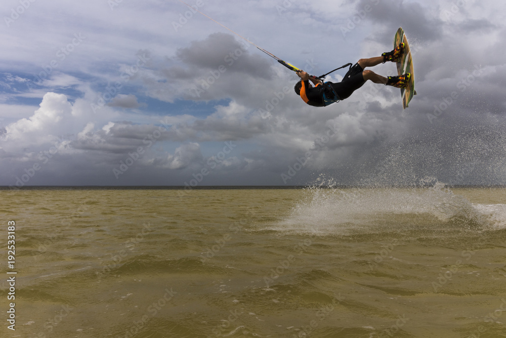 Fototapeta premium Kitesurfer jumps and flies with a kite and a board on water on a sunny day