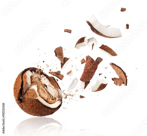 Broken coconut with splashes of juice close-up, isolated on white background