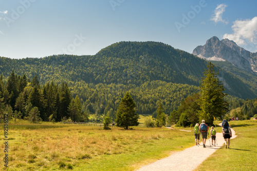 Alpine valley in summer, road, group of people hiking