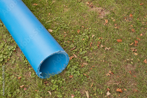 Ein abgesägtes blaues Rohr aus Kunststoff für eine neue Wasserleitung liegt auf dem Rasen