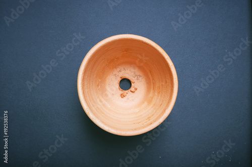 Empty orange clay flowerpot top view with black background.
