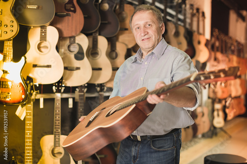 Male musician buying new acoustic guitar