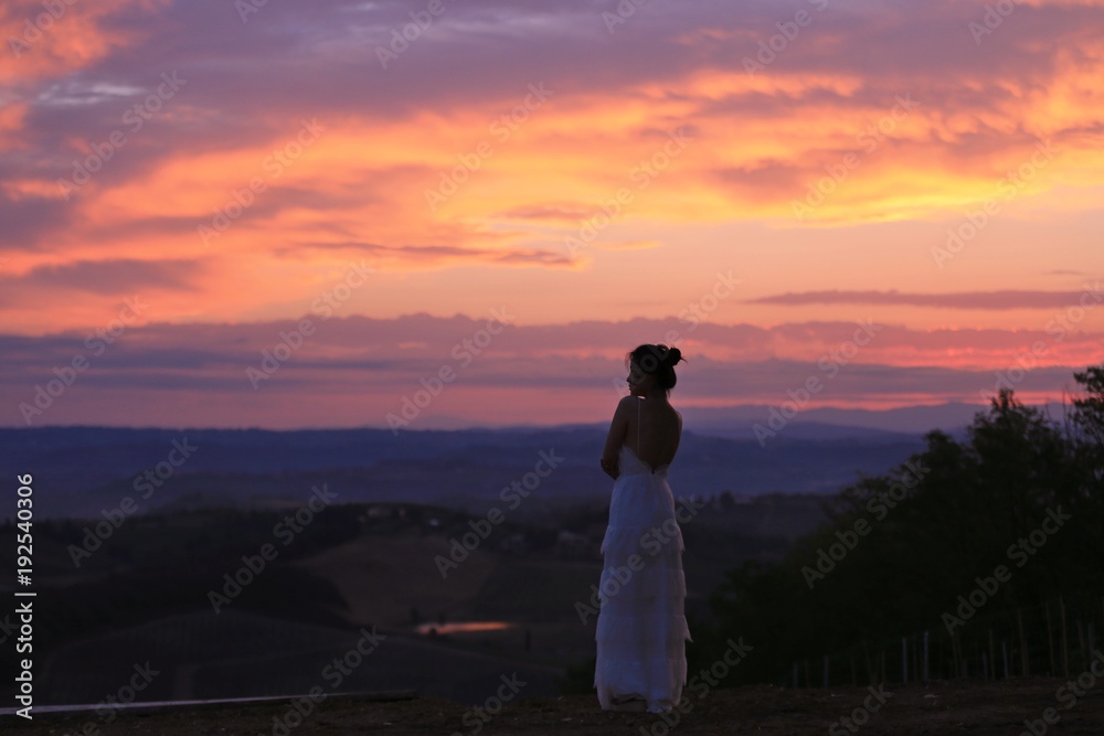 an Asian woman in white dress standing under the sunrise in Tuscany, Italy an Asian woman in white dress standing under the sunrise in Tuscany, Italy