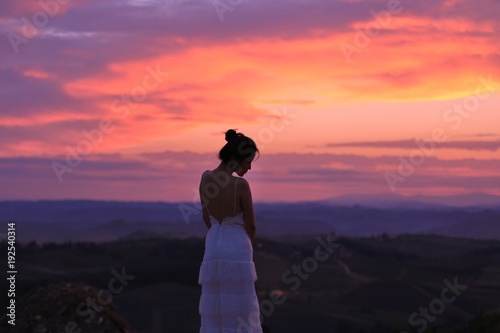 an Asian woman in white dress standing under the sunrise in Tuscany  Italy