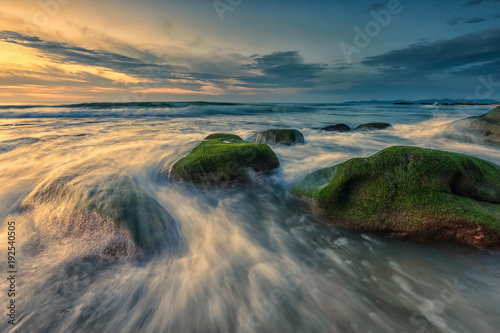 colorful sunset seascape with natural coastal rocks covered by green moss at Kudat Sabah Malaysia. 