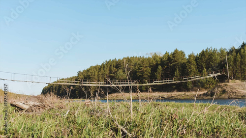 Wooden bridge and field. Video. A small wooden bridge over a creek. Grass, blue sky, reeds. A wooden bridge is made for crossing a rice field. photo