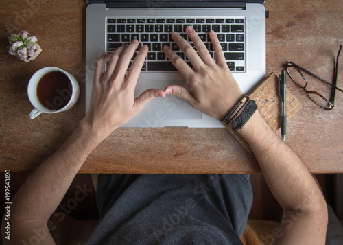 Vintage but modern author and writer, wooden laptop on desk. Male hands using a laptop and holding a cup of coffee. such scenes are good for authors, writers, editors or journalists