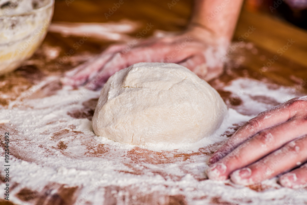 Fototapeta premium male baker hands kneading dough on wooden table. mass of dough on a table