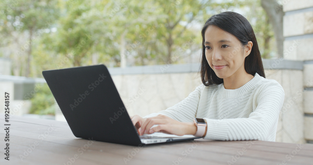 Woman typing on notebook computer at outdoor Woman typing on notebook computer at outdoor