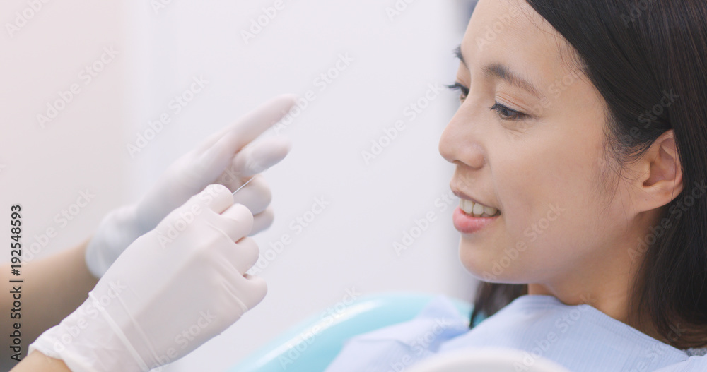 Dentist teaching patient how to use dental floss