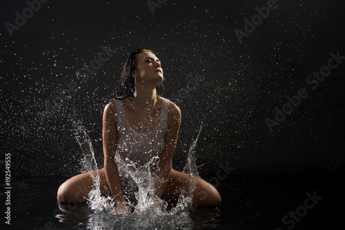 Pretty girl playing with water in dark room