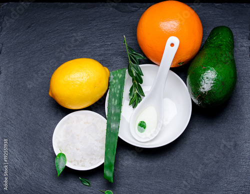 Sea cosmetic salt in a white pial with aloe orange lemon and avakado on a slate board photo