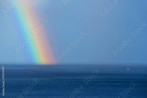 Beautiful rainbow and boat on the ocean horizon