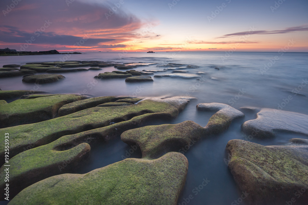 Obraz premium colorful sunset seascape with natural coastal rocks covered by green moss at Kudat Sabah Malaysia. 