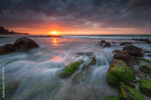 vibrant sunset color with beautiful rocks formation covered by green moss. image may contain soft focus due to long expose.