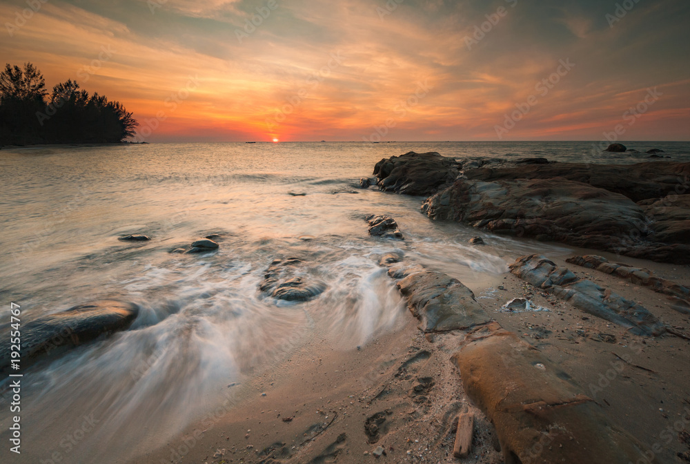 Naklejka premium long expose sunset seascape with waves trails. image contain soft focus due to slow shutter.