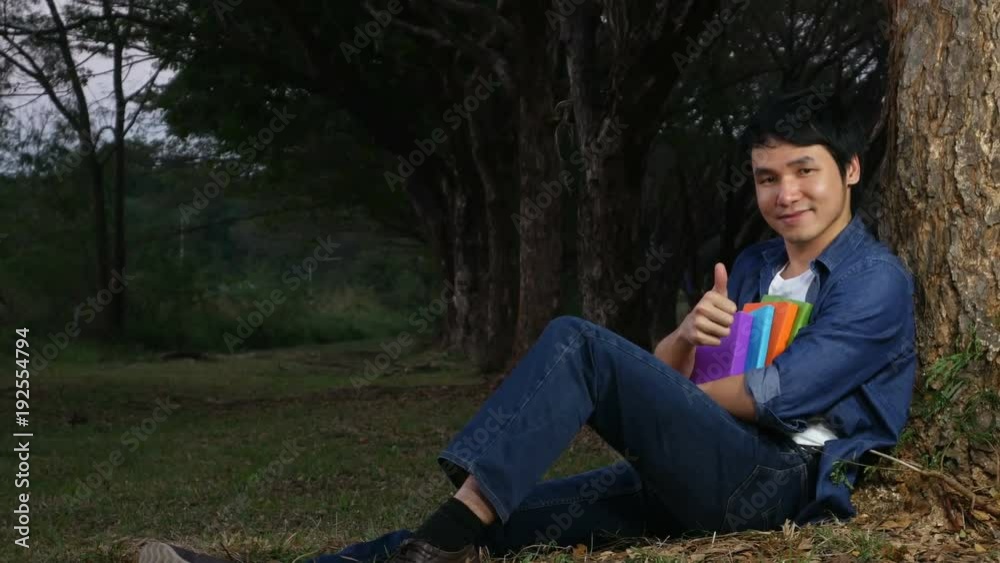 4k video of cheerful man holding a book with thumbs up in the park 4k video of cheerful man holding a book with thumbs up in the park