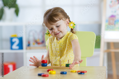 Smart child girl plays in kindergarten in Montessori preschool class.