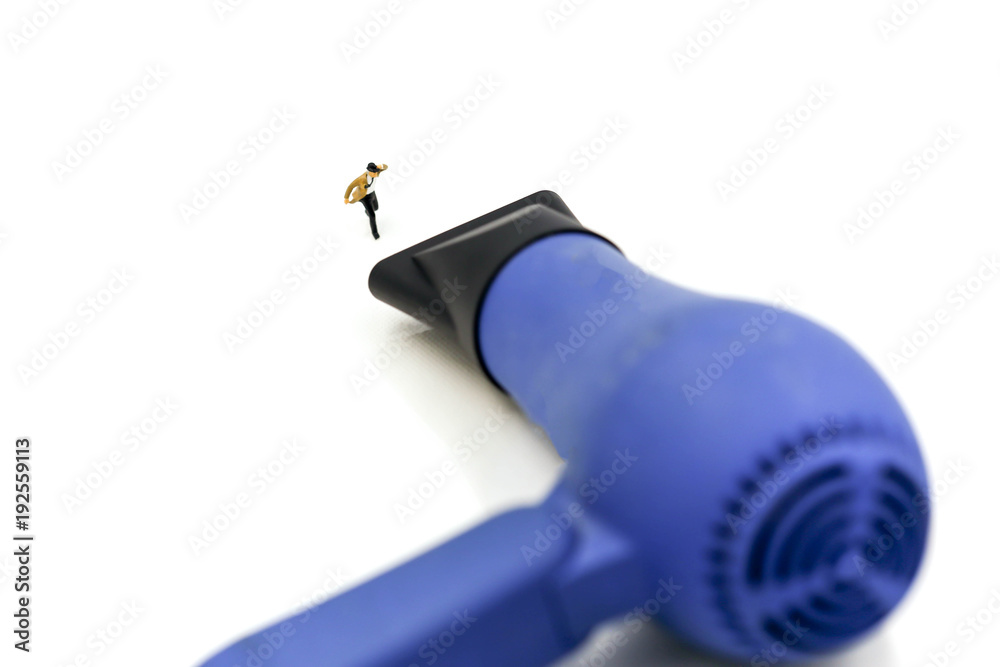 Miniature people :  businessman and Tie blowing in wind stand with hair dryer.