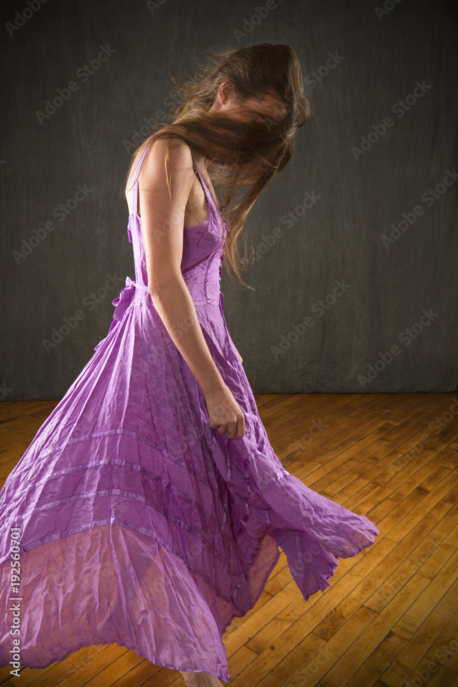 Obraz premium Young woman in lavender dress dancing in the studio.
