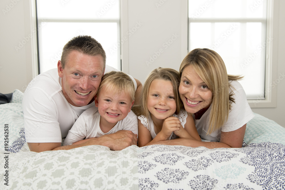 young beautiful and radiant couple 30 to 40 years old smiling happy posing sweet lying on bed with little son and beautiful daughter at home young beautiful and radiant couple 30 to 40 years old smiling happy posing sweet lying on bed with little son and beautiful daughter at home