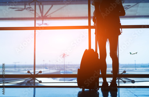 Silhouette woman travel with luggage looking without window at airport terminal international or girl teenager traveling in vacation summer relaxation holding suitcase and backpack photo