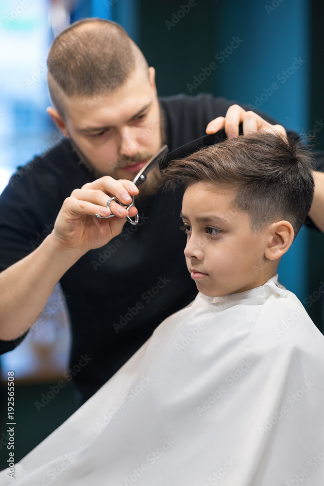 the young man the hairdresser cuts the schoolboy in hairdressing salon the young man the hairdresser cuts the schoolboy in hairdressing salon