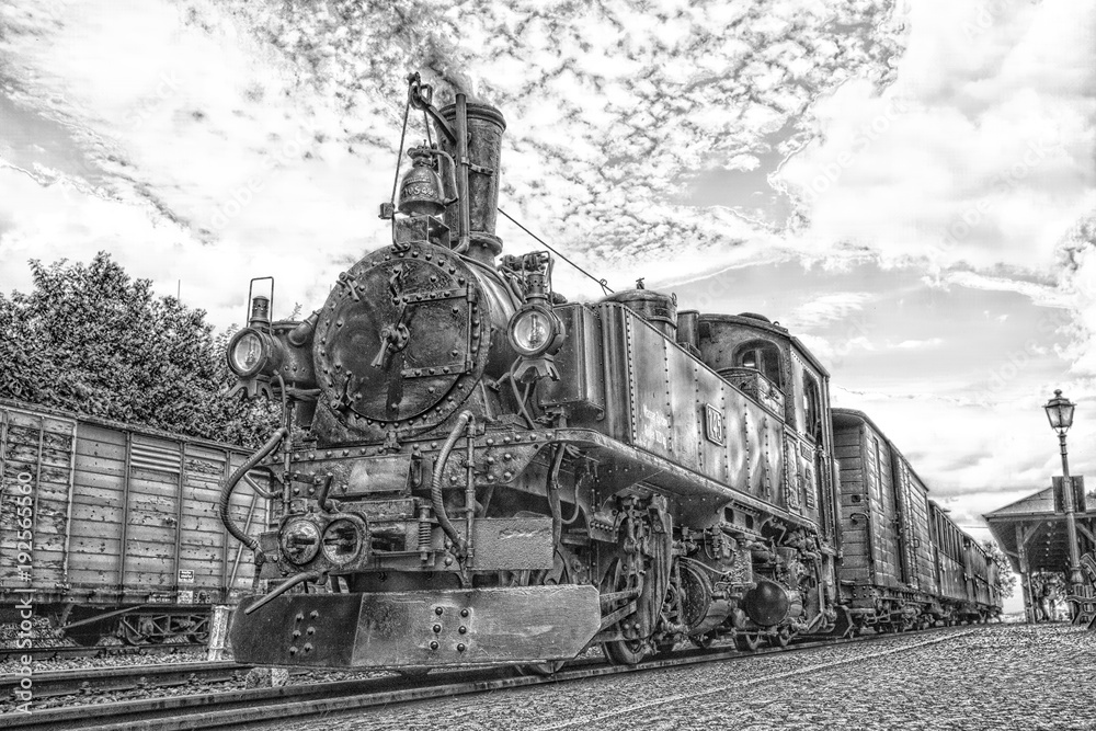 Fototapeta premium Historic steam powered railway train at train station in black and white