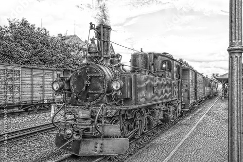 Historic steam powered railway train at train station in black and white