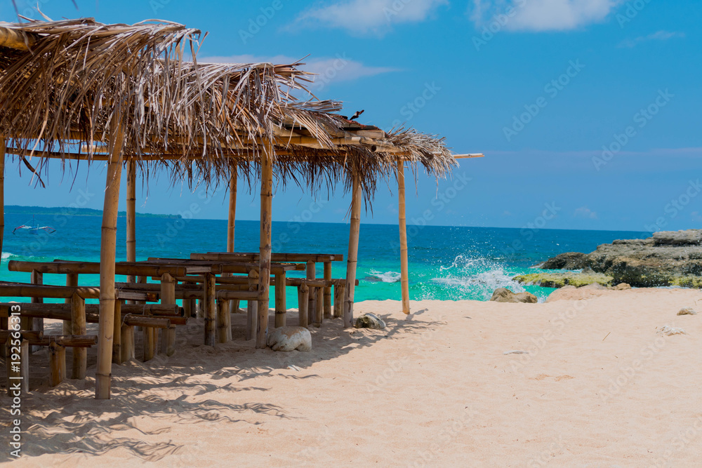 tropical beach with bamboo chairs and nipa hut umbrellas
