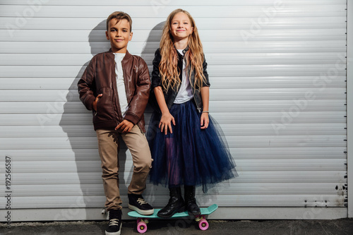 Portrait of two teenage school children on a garage door background in a city park street.