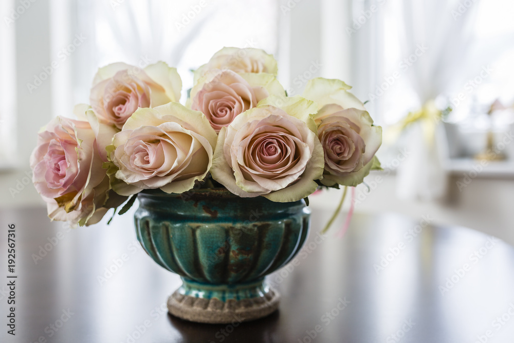 Obraz premium A bouquet of beautiful roses in an vintage vase on the table.