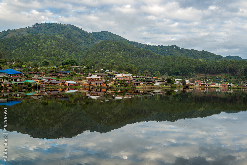 Fototapeta premium Water Village at the edge of river in front of the mountain in countryside of Thailand