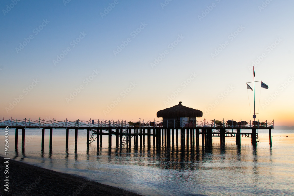 The bungalow on the pier is flooded with sunlight. Blue from the dawn sky.