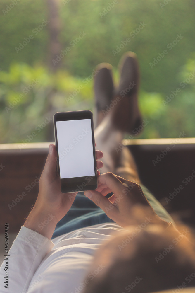 Man lying on a sofa and using cellphone.