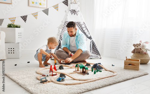 happy family father and child son playing   in toy railway in playroom