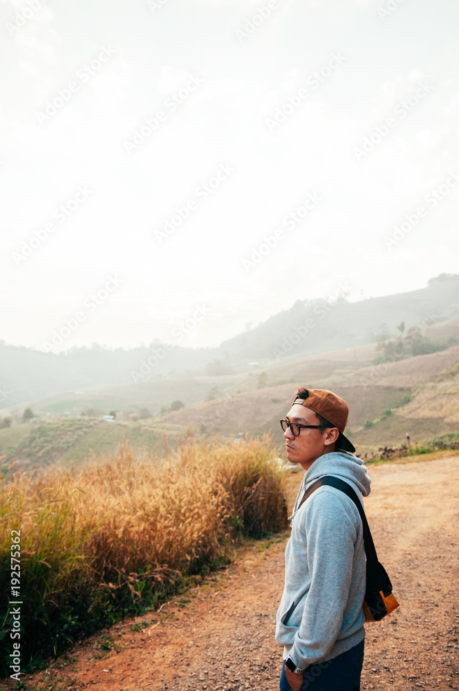 Happy asian woman in morning light holding camera sit on fence at mountain top with beautiful hills background