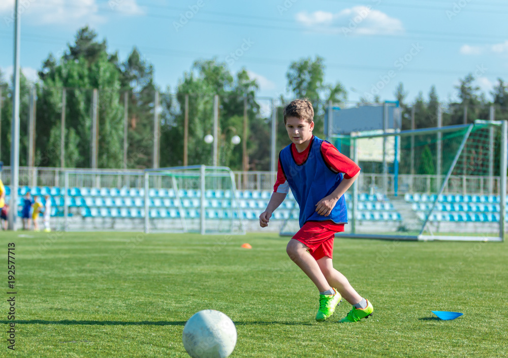 boy trains dribbling on the summer stadium during the training