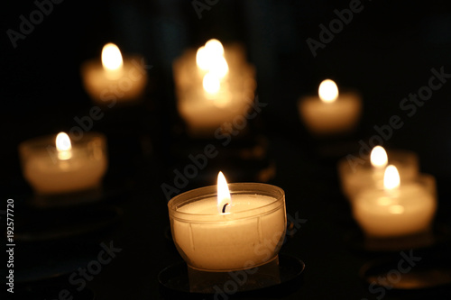 White candles burning in dark church close up