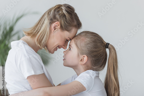 close-up portrait of mother and daughter embracing and cuddling